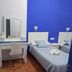 The Dreamers&Co, Córdoba: twin beds, blue accent wall, and vanity desk in a simple guest room