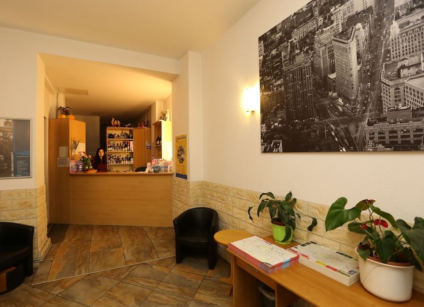 Hotel Ai Königshof Berlin lobby with reception desk, chairs, potted plants and city wall art