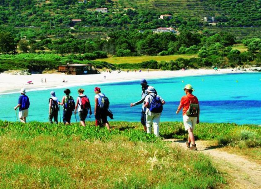 Feriendorf Zum Stoerrischen Esel in Calvi, hillside path to a turquoise bay with beachgoers