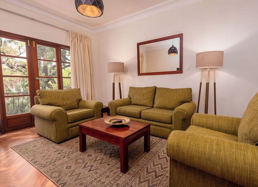 Bronte Hotel Harare living room with sofas, coffee table, rug and French doors to balcony