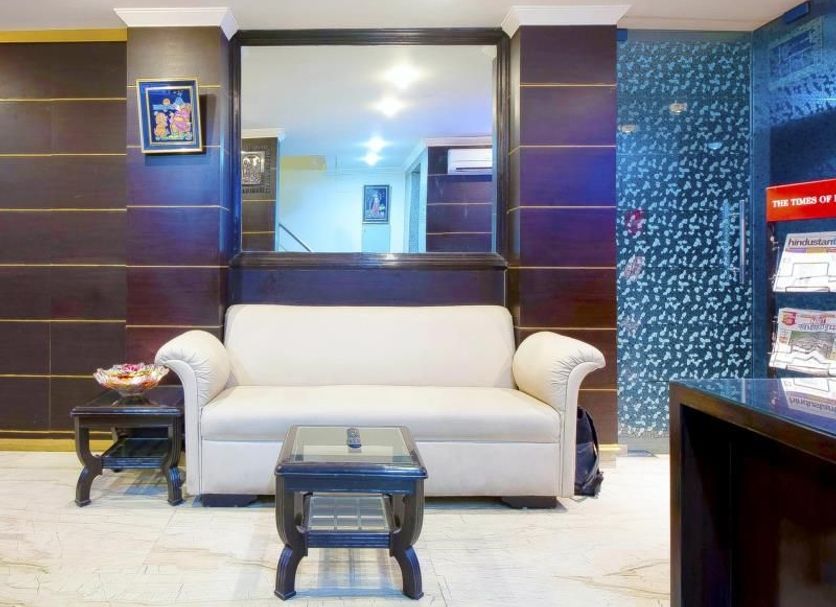 Amrit Villa, New Delhi lobby with white sofa, coffee tables, wall mirror and brochure stand