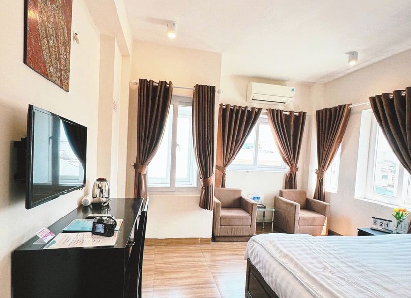 Canary Boutique Hotel in Hue guest room with bed, TV, armchairs, windows and curtains