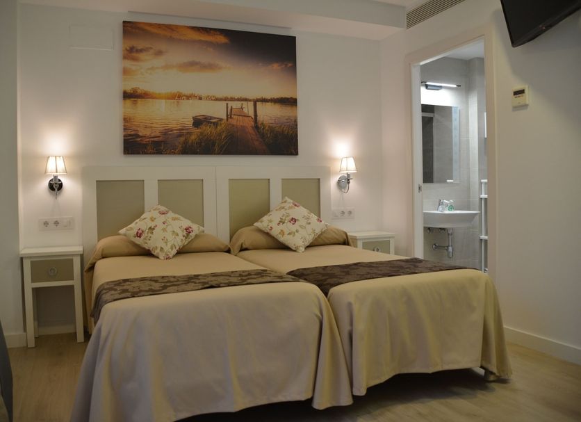 Hotel Doña Lina Seville twin room with framed waterfront wall art and bedside lamps