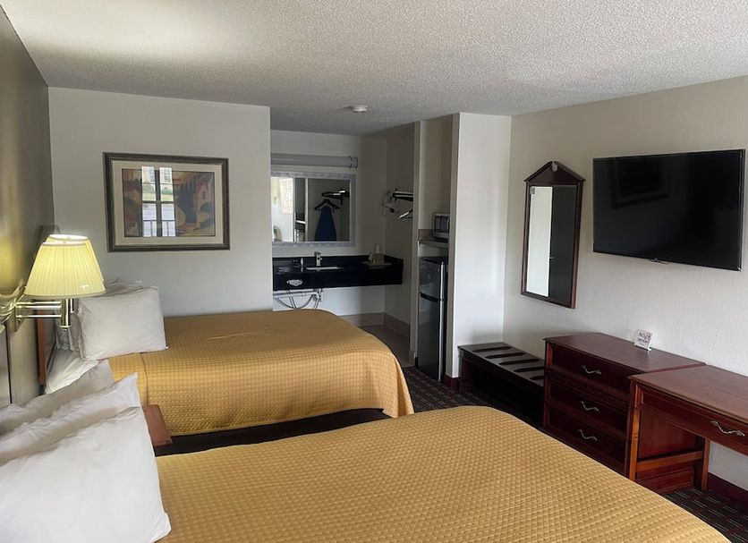 Loyalty Inn Hawkinsville room with two beds, wall-mounted TV, desk, dresser, and lamp