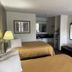 Loyalty Inn Hawkinsville room with two beds, wall-mounted TV, desk, dresser, and lamp