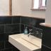 The White House in Bishop's Stortford bathroom with black tile walls, white sink, and window light