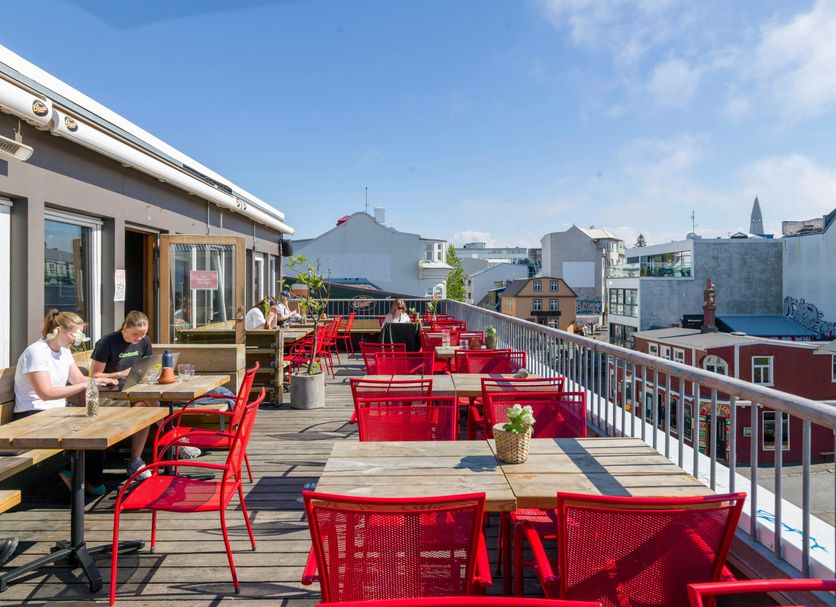 Loft - Hi Eco Hostel rooftop terrace in Reykjavik with red tables, chairs and city views