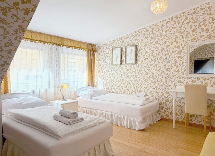 Allegro Hotel Ljubljana room with two single beds, floral wallpaper, and a small vanity desk
