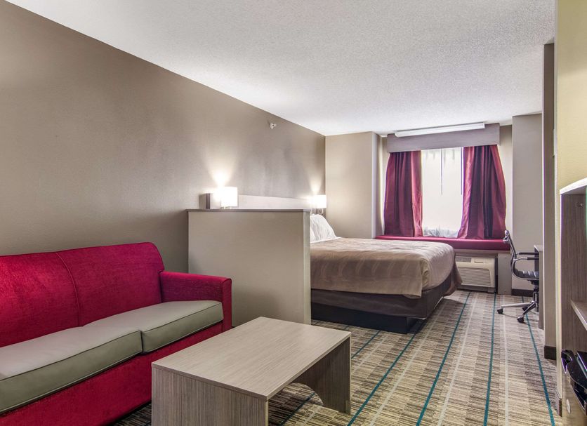 Quality Inn & Suites Grove City-Outlet Mall guest room with bed, sofa and window in Grove City