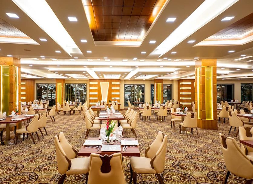 Royal Swiss Lahore in Lahore: spacious banquet hall with set dining tables, ornate carpet, and warm ceiling lights