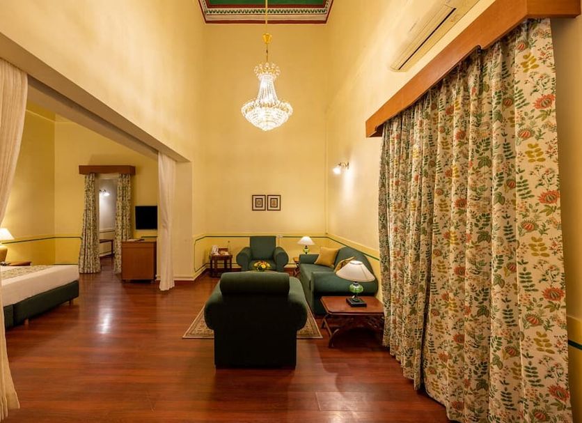 Umed Bhawan Palace in Kota suite with chandelier, seating area, bed alcove and floral curtains