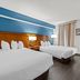 Baymont by Wyndham Tuscaloosa guest room with two queen beds, blue accent wall, and desk