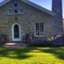 Maxwelton Braes Lodge in Baileys Harbor: stone lodge exterior with chimney, patio chairs and landscaped lawn