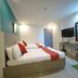Legazpi Tourist Inn room in Legazpi City with two beds, wall-mounted TV, desk, and mirror
