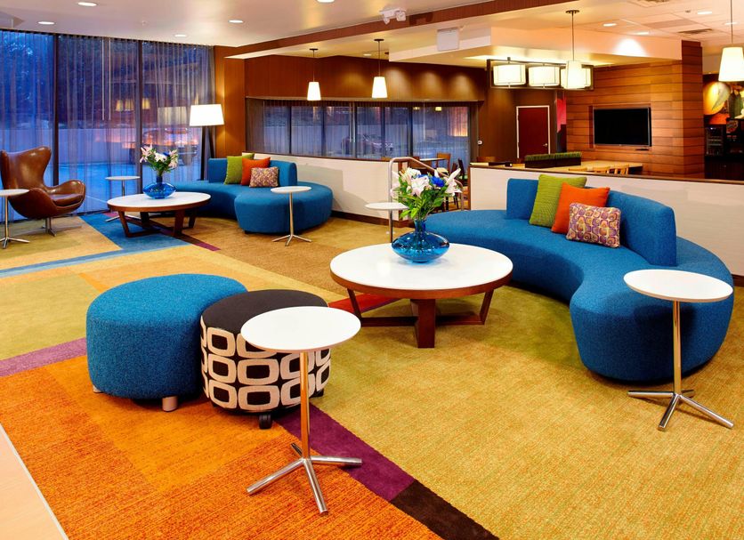 Fairfield Inn & Suites Parsippany lobby lounge with blue curved seating, tables and warm lighting