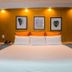 Le Plaza Hotel in Port Au Prince guest room with king bed, warm wall lighting, and framed leaf art