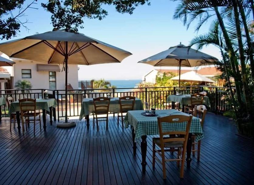 Fairlight Beach House, Umhlanga: outdoor deck dining with sea view, tables, umbrellas and palm trees
