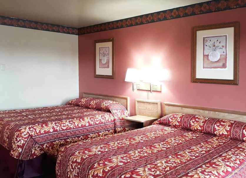 OYO Hotel Kings At Clovis guest room with two double beds and patterned red bedding in Clovis