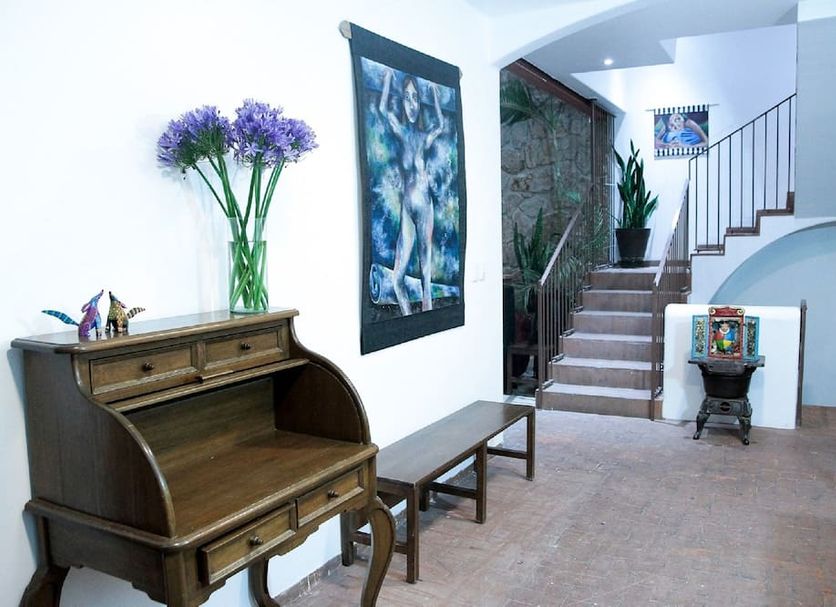 La Cochinilla Hotel Boutique in Oaxaca lobby with wooden desk, bench, stairs and potted plants