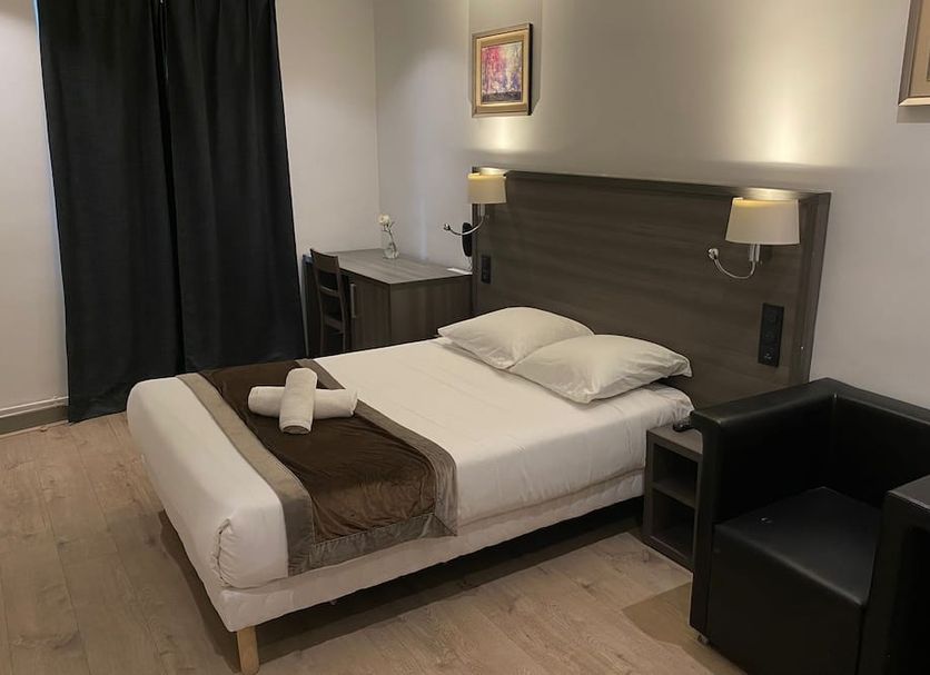 Hôtel Résidence Châtillon in Paris guest room with single bed, armchair and wall-mounted lamps