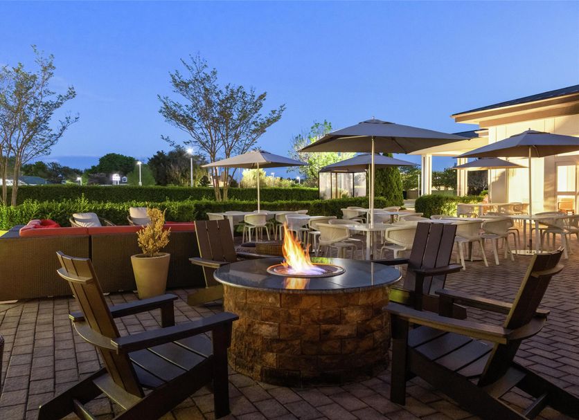 Hilton Garden Inn Riverhead outdoor fire pit with seating and patio dining at dusk