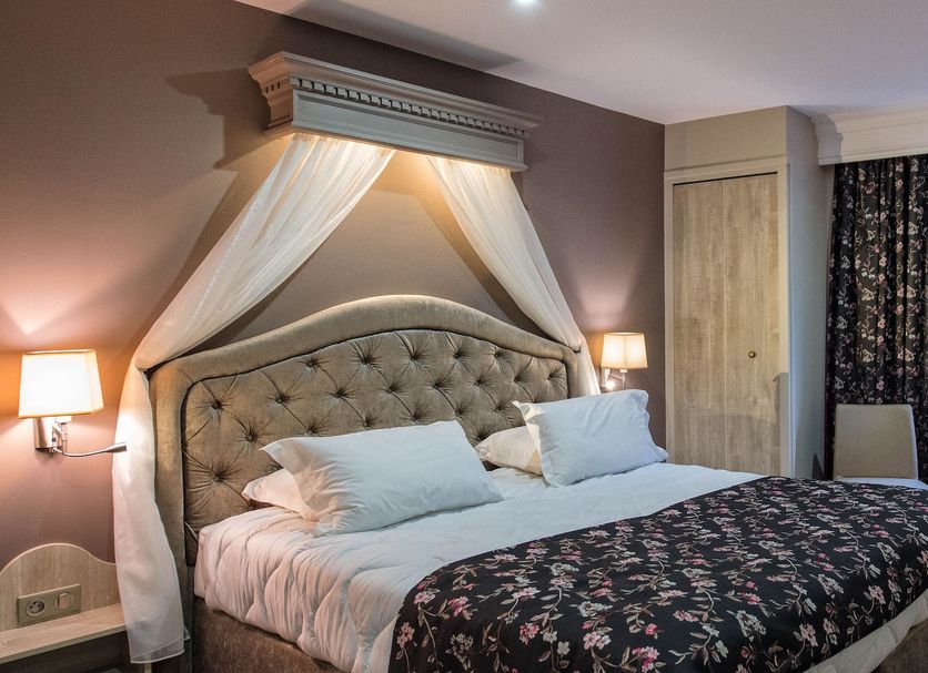 La Terrasse in Douai guest room with a canopy bed, floral bedspread, and seating area