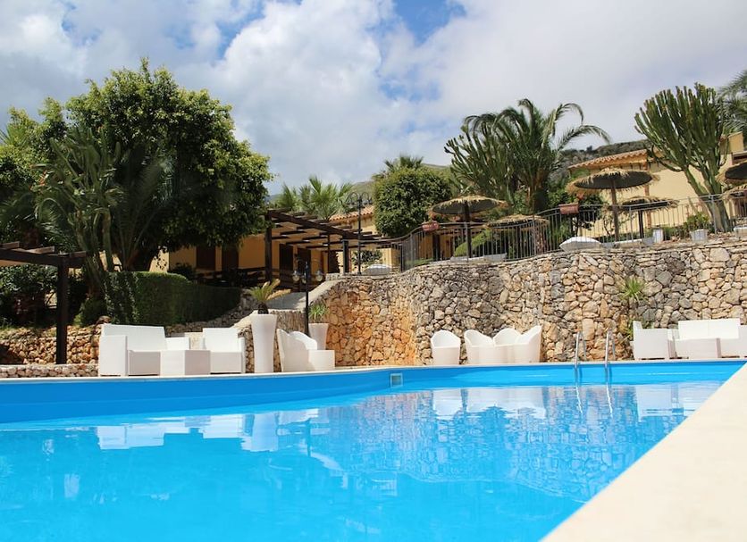 Hotel Grotticelli in Scopello with an outdoor pool, stone terrace, and lush hillside garden