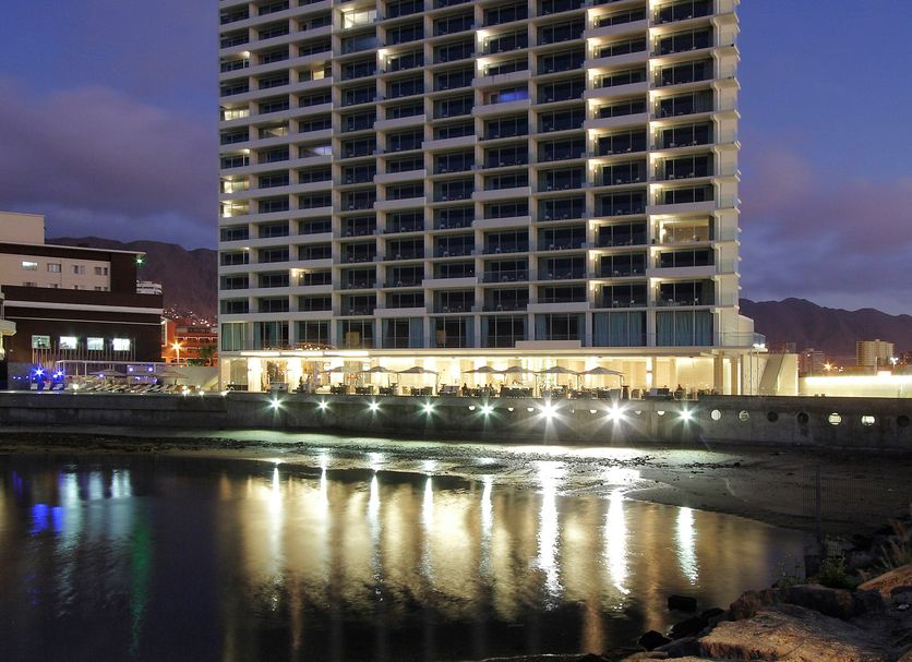 Terrado Suites Antofagasta high-rise hotel beside the water at dusk in Antofagasta