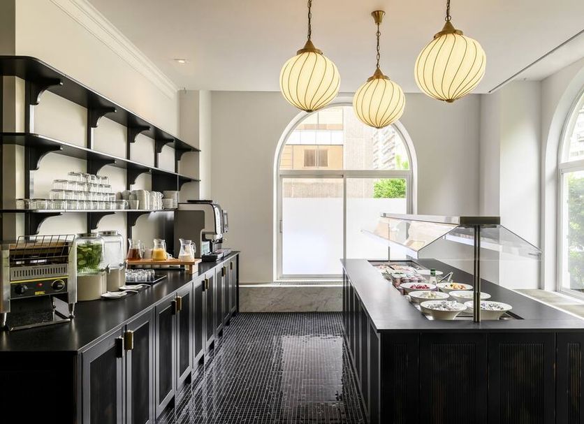 Breakfast buffet area at a&o Brussel Centrum in Brussels with arched windows and hanging pendant lights