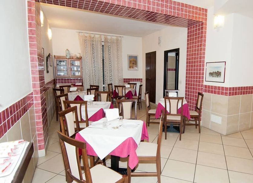 Hotel Chopin Genoa dining room with set tables and red-tiled archway