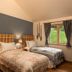 The Whispering Pine Lodge in Spean Bridge guest room with twin beds, bedside lamps and a window to green hills