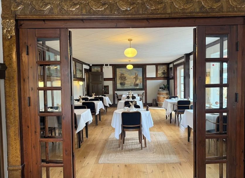 Hotel Strandly Skagen dining room with set tables, wooden floors and tall windows in Skagen