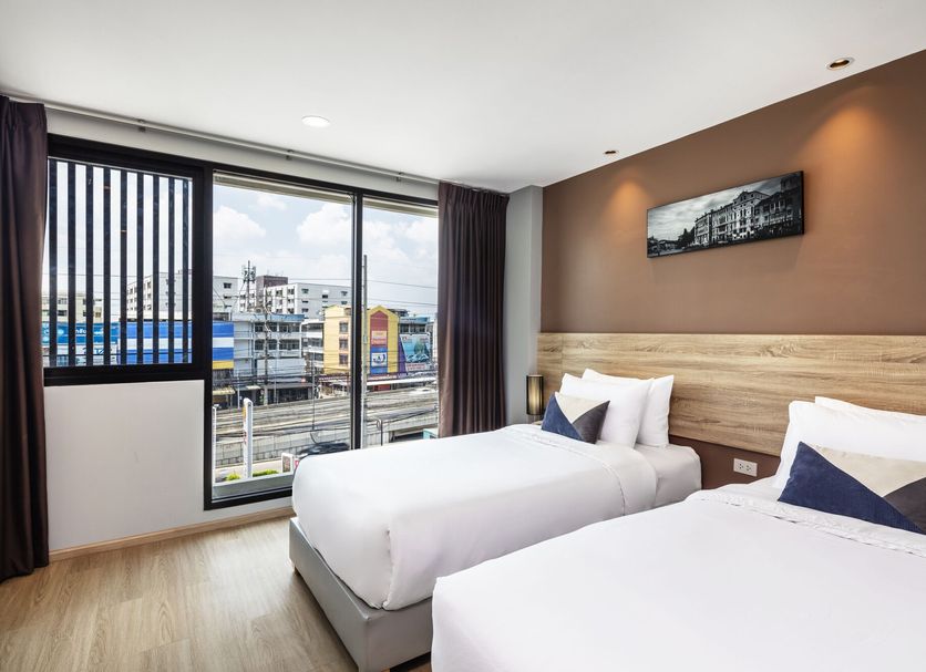 Narra Hotel in Bangkok guest room with two beds and a city view through large windows