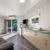 Tasman Holiday Parks - Christchurch cabin interior with kitchenette, sofa, dining table and glass doors to deck