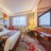 Yichang Guobin Bandao Hotel room with queen bed, desk, large window, and wall-mounted TV in Yichang