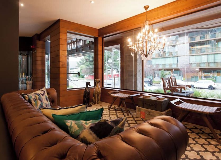 Hotel Cercano in Gramado lounge with tufted sofa, chandelier, and large street-facing windows