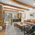 Antlers at Vail living room with stone fireplace, wood beams, sofa, and mountain-view window