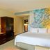 Courtyard by Marriott San Salvador guest room with king bed, desk, wardrobe and colorful mural wall