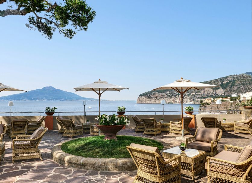 Grand Hotel Ambasciatori in Sorrento terrace with wicker seating, umbrellas, and sea views over the bay