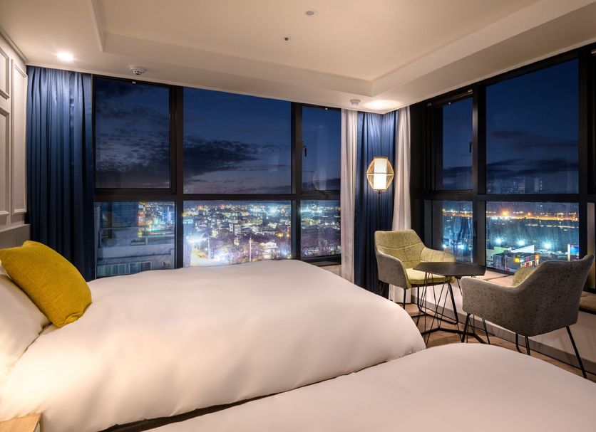 Ventimo Hotel & Residence Jeju room with floor-to-ceiling windows and city lights in Jeju City