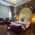 Vong Xua Hotel Hanoi guest room with bed, seating area, wood floors and arched decorative headboard