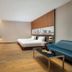 The Mulian Hotel Guangzhou Zhujiang New Town room with twin beds, sofa, and city skyline wall art