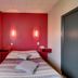 Logis Auberge des Vieux Chênes in La Chapelle-aux-Brocs, simple guest room with red accent wall and bed