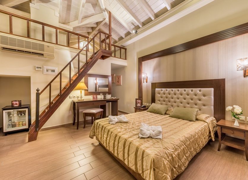 Theofilos Paradise Boutique Hotel in Mytilene: loft-style guest room with staircase, wood accents and king bed
