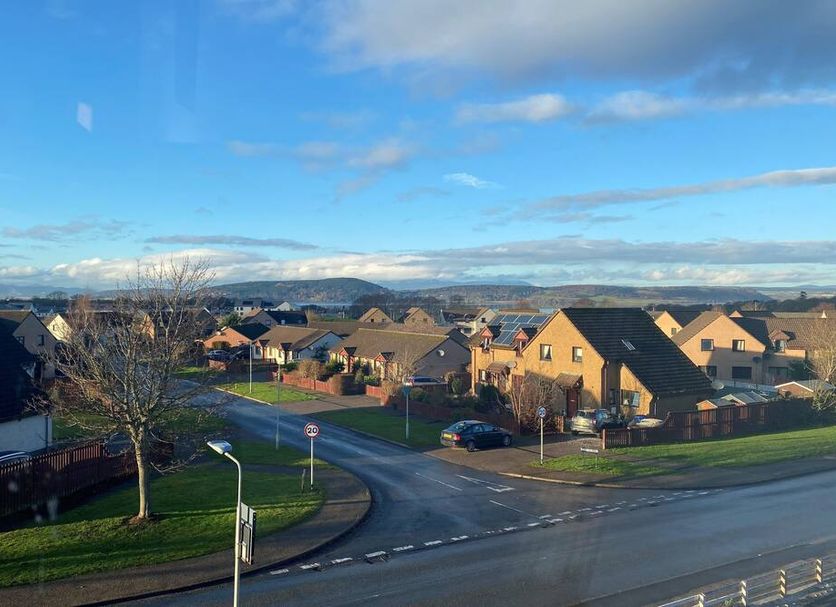 Smithton Hotel in Inverness overlooks a quiet suburban road with houses and distant hills under blue sky.