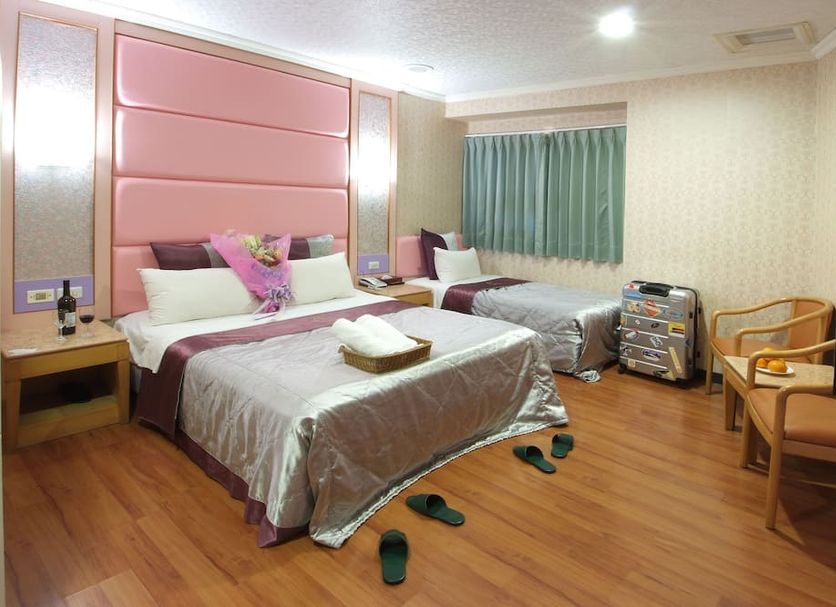 Left Bank Hotel Hsinchu City guest room with two beds, TV, chairs, and wood flooring