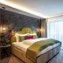 Hotel Jägerhof Mayrhofen guest room with floral accent wall, king bed, and armchair by window