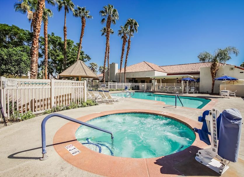 Desert Breezes Resort in Palm Desert with outdoor pool, hot tub, and palm trees under clear blue sky