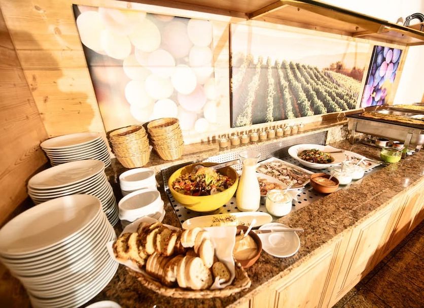 Landhotel Kauzenberg breakfast buffet with bread, fruit, cereal, and stacked plates in Bad Kreuznach