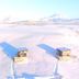 Afternoon Cottages in Hella with three small cabins on a snowy landscape and distant mountains